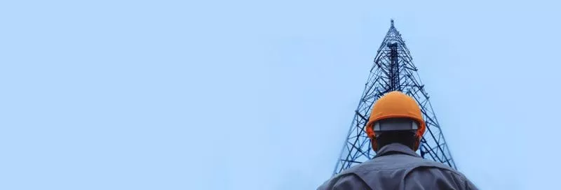 Technician Climbing Telecommunication Tower Under Cloudy Sky